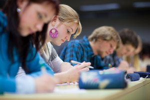 Pretty female college student sitting in a classroom full of stu