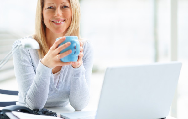 Portrait of mature business woman with a laptop and drinking cof